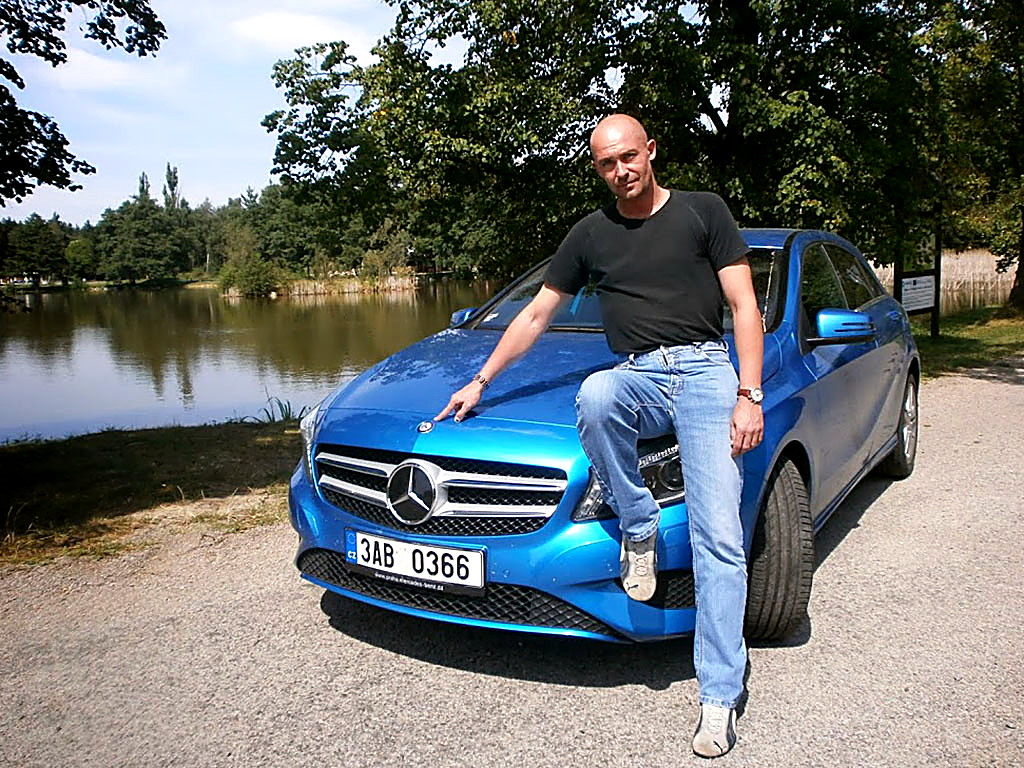 Petr Jansa sedí na kapotě modrého Mercedesu třídy A u rybníka