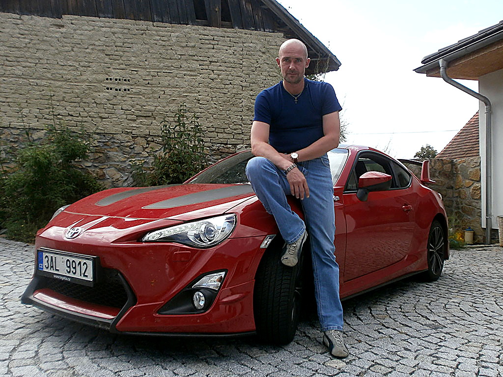Petr Jansa sedí na kapotě červené Toyoty GT86