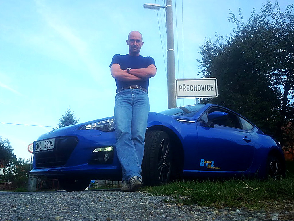 Petr Jansa opřený o modrou Subaru BRZ u silnice