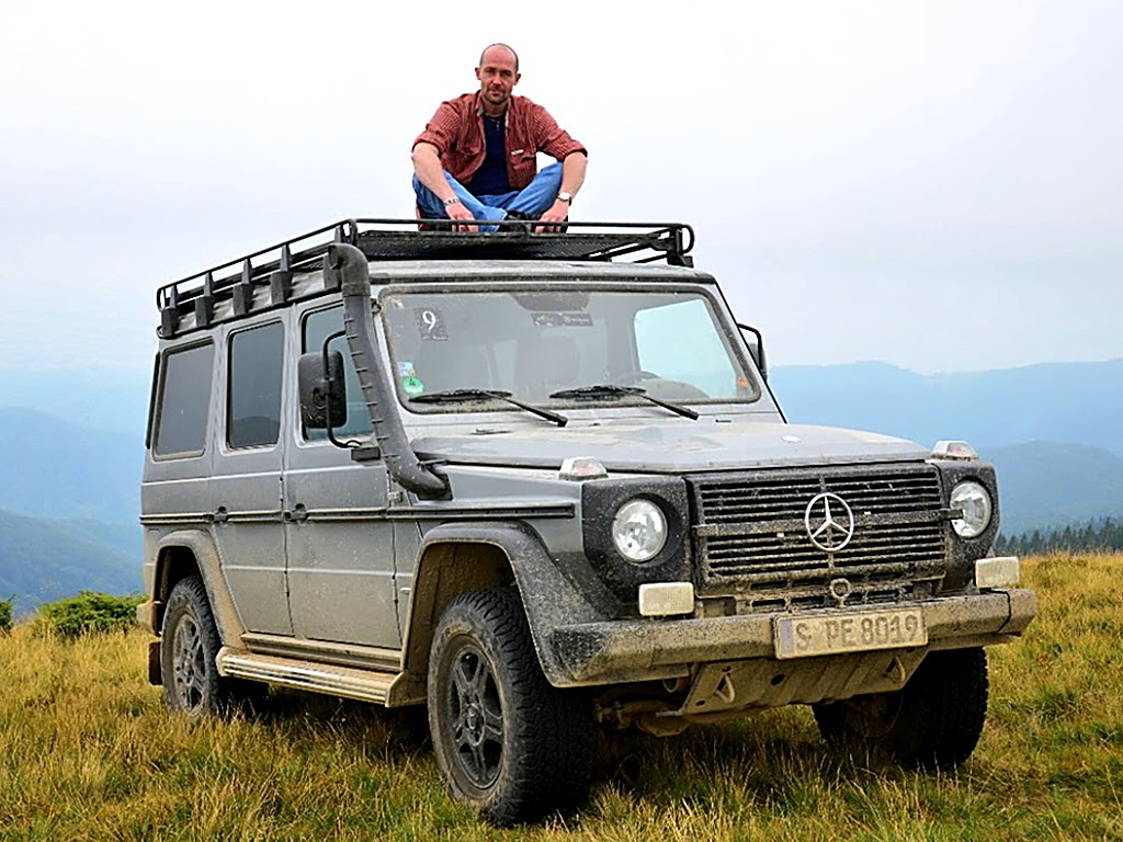 Petr Jansa sedí na střeše Mercedesu třídy G v horách